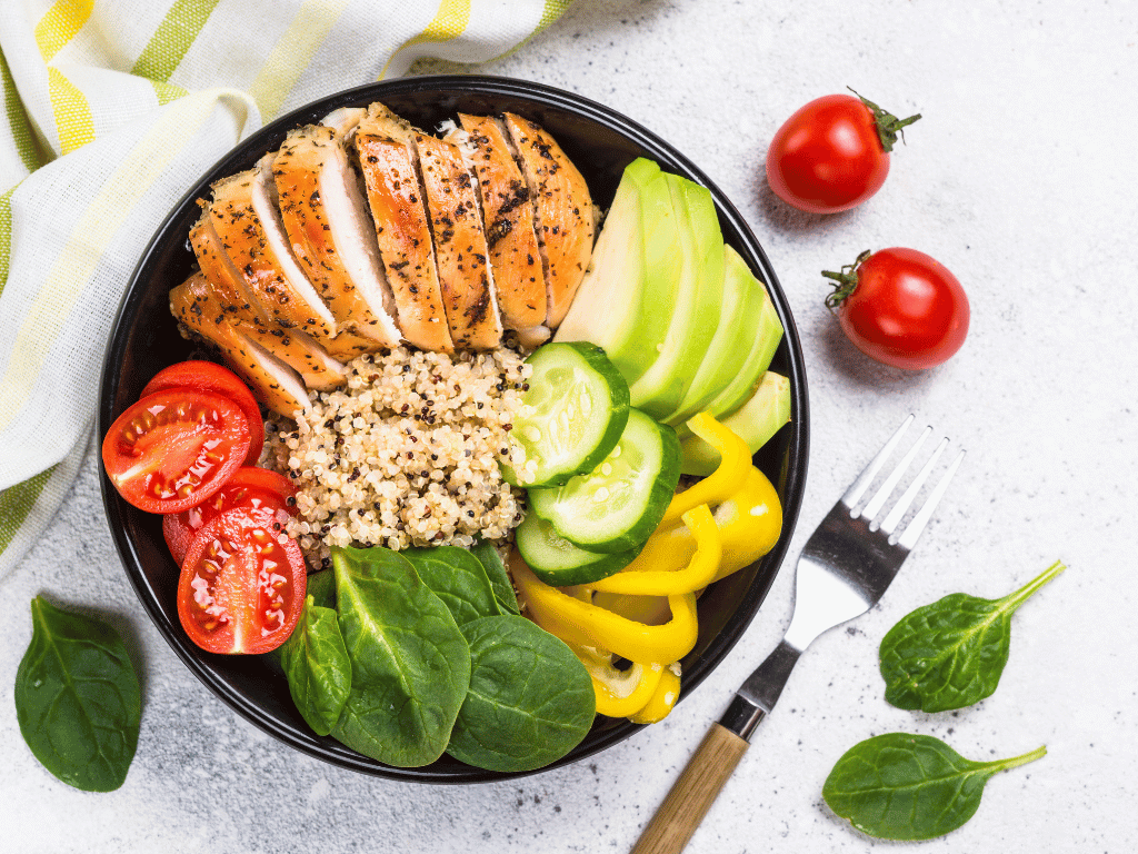 A colorful plate of low-GI foods including quinoa, grilled chicken, and vegetables, representing a balanced meal for blood sugar control